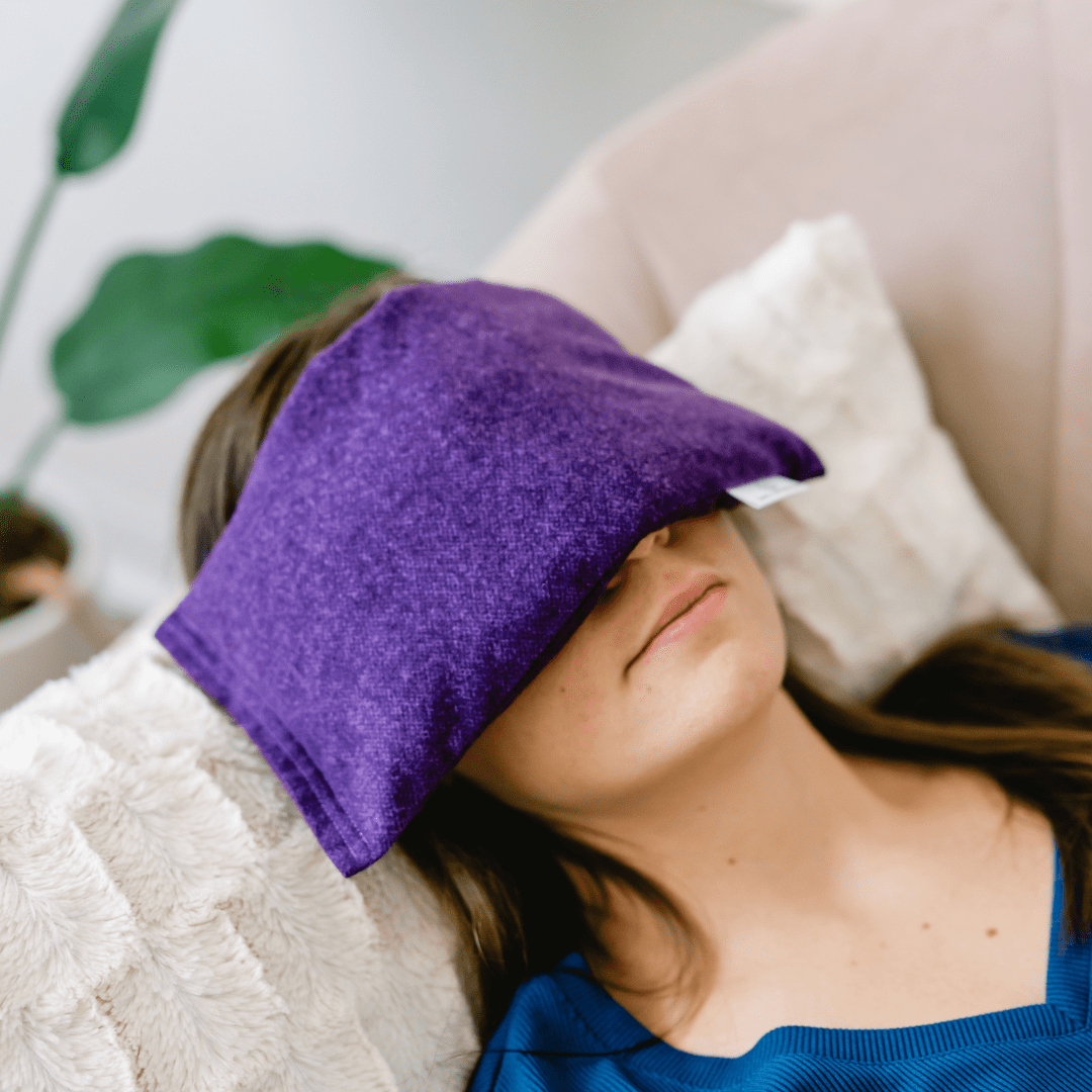 Purple weighted eye pillow covering a woman's eyes, designed for relaxation.